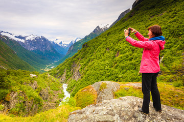 Fototapeta na wymiar Tourist with camera taking picture in mountains Norway