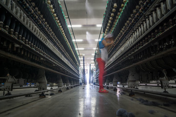 female worker standing beside thread making machine inside cotton mill,industry concepts.