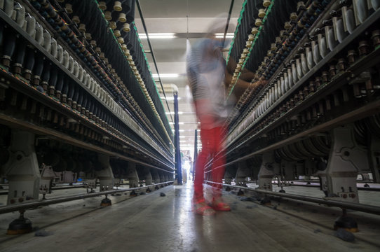 female worker standing beside thread making machine inside cotton mill,industry concepts.