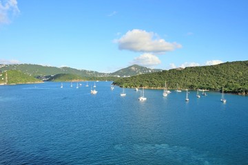 Sailboats on the ocean with mountains in the background and a beautiful blue sky