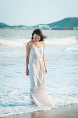 Fototapeta na wymiar Woman standing in wave on beach in summer. Happy multiracial Asian girl going to sea.