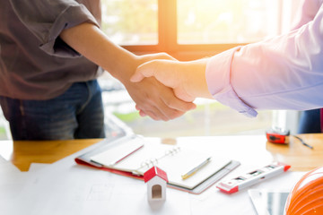 Two confident business man shaking hands during a meeting in the architect office, success, dealing, greeting and partner concept.