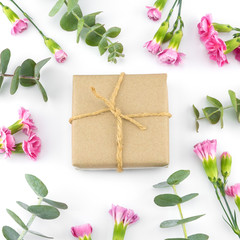 Brown gift boxes decorated with baby eucalyptus leaves and pink carnation flowers on white background
