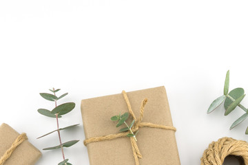 Brown gift boxes and ropes decorated with baby eucalyptus leaves with copy space on white background