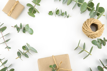 Brown gift boxes and ropes decorated with baby eucalyptus leaves with copy space in the center on white background