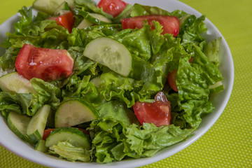Fresh salad. Tomato, cucumber and greens in white bowl