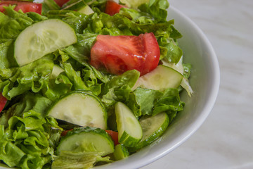 Fresh salad. Tomato, cucumber and greens in white bowl