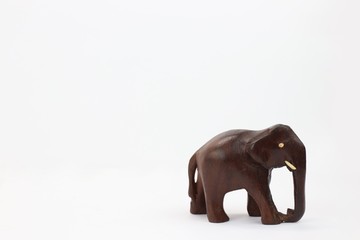 hand carved wooden elephant standing facing right isolated on white background 