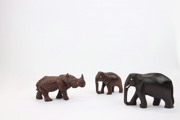 Two hand carved wooden elephants facing wooden rhinoceros 