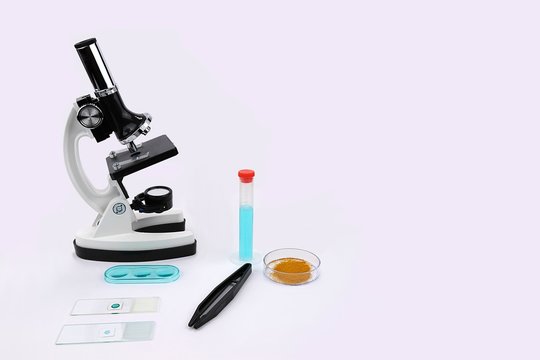 Microscope with slides and forceps and other lab equipment centered left 