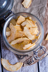 Top view of jar with fruit apple and banana chips on wooden table background. Sweet vegan healthy dessert. Copy space