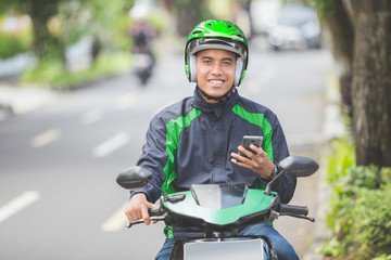 motorcycle taxi driver taking order via mobile phone online app