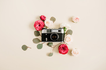 Vintage retro camera, red and beige rose flower buds pattern on pale pastel beige background. Flat lay, top view decorated concept.