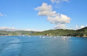 Sailboats on the ocean with mountains in the background and a beautiful blue sky