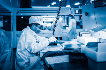 workers and machinery in a solar panel manufacturing industry factory.