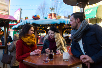 Freude treffen sich auf einem Weihnachtsmarkt und stoßen mit Glühwein an