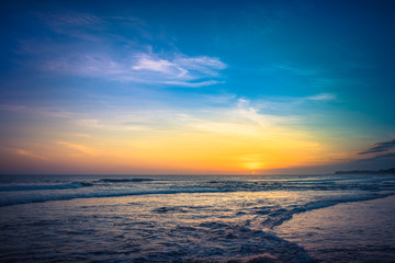 Naklejka na ściany i meble Sunset Background Ocean. Tropical Sunlight and Summer Sunset View. Colorful Background Sunset. Blue Waves near sea Resort. Sea sunset Background. Colorful Beach with Surfers on the Horizon. Landscape