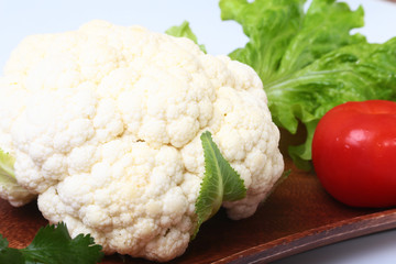 fresh cauliflower, tomato, salad leaves and other vegetables on wooden board. Ready for cooking. Vegetarian food.