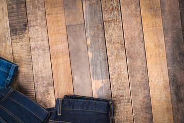 Jeans on wood background, top view