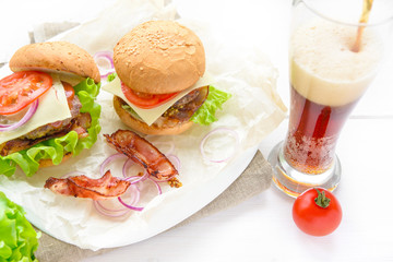 Two burgers served with glass of soda on white table