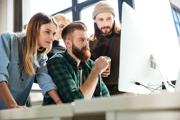 Happy colleagues in office using computer
