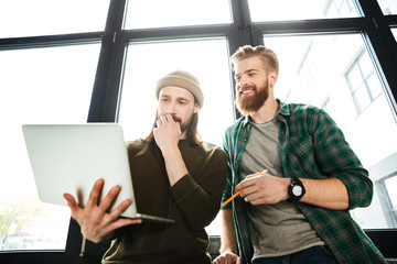 Young concentrated men colleagues in office using laptop