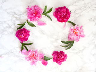 Flat lay frame with pink peonies, leaves and petals. Top view