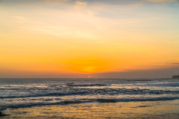 Fototapeta na wymiar Sunset beach in Bali - Echo beach. Waves, tide and magic sea landscape view with a beautiful evening sky. Indonesia, Ocean. Orange beach pattern. Surfing Waves on the Tropical Beach. Panoramic Sunset
