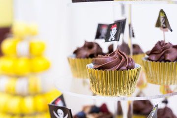 Close-up of cupcakes on stand in yellow and black colors, pirate theme for kids birthday party