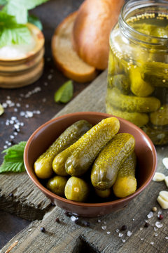 Marinated cucumbers gherkins. Pickles with mustard and garlic on a stone background.