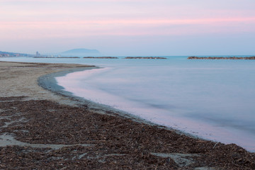 A sea shore at dusk, with beautiful warm and soft colors in the sky