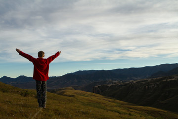 boy praising and enjoying mountains and landscape