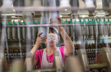 female worker standing beside thread making machine inside cotton mill,industry concepts.