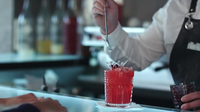 Bartender decorating cocktail red alcoholic cocktail with berries