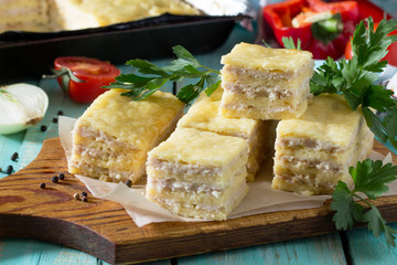 Meat cake made of minced meat and cheese on a kitchen wooden table with fresh vegetables. The concept of a healthy diet.