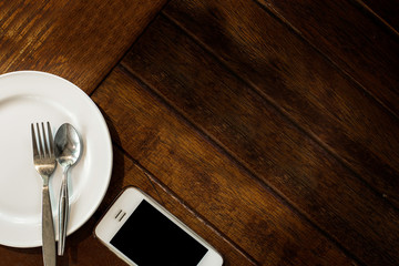 An empty white dinner dish with set on a rustic wooden table top background.