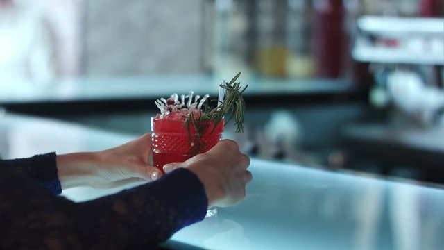 female hands holding red cocktail in the bar