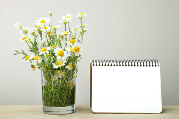 Notebook and vase with chamomiles