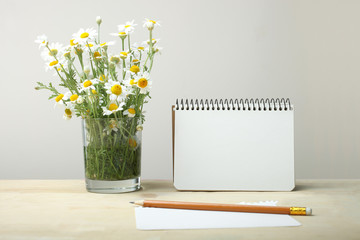 Notebook and vase with chamomiles