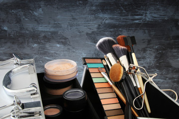 Fototapeta na wymiar makeup cosmetics beauty tools and brushes infront of black wooden background