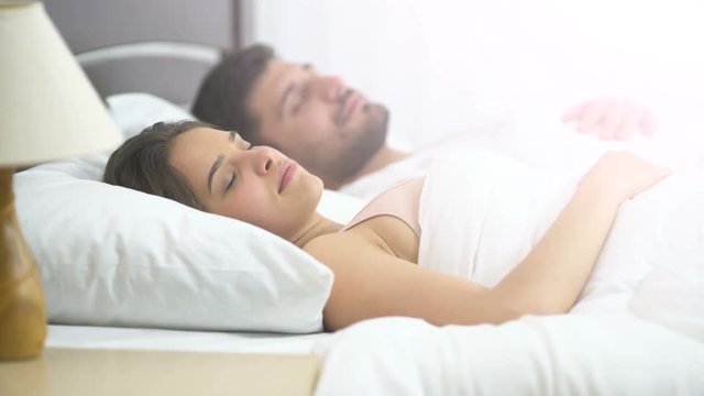 The attractive woman sleeping near the man on the bed