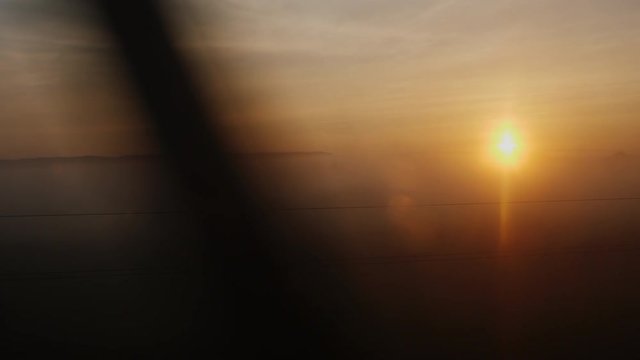 Sunrise over the countryside. View from the window of a moving train