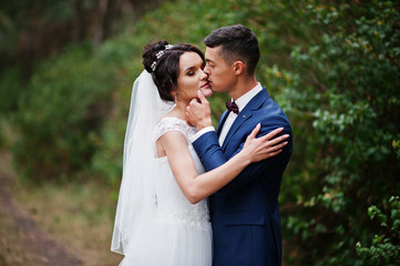 Close-up photo of a wedding couple kissing in the pine forest.
