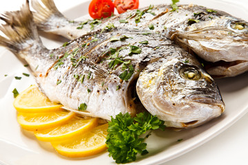 Fish dish - roast fish and vegetables on white background