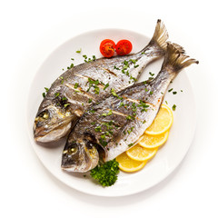 Fish dish - roast fish and vegetables on white background