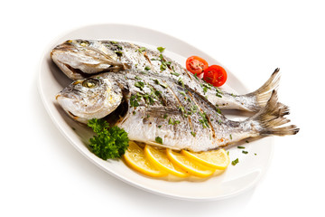 Fish dish - roast fish and vegetables on white background