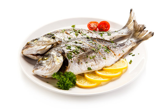 Fish dish - roast fish and vegetables on white background