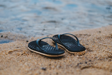 black sandal putting on sand beach. have pond water are background. this image for nature and equipment concept
