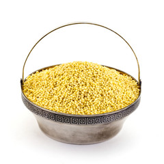 Dry millet in silver bowl isolated on white. Spilled millet.