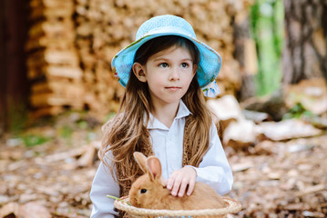 brunette girl in hat holding a rabbit